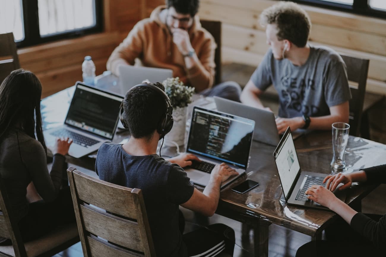 A mixed group of students coding on laptops around a table